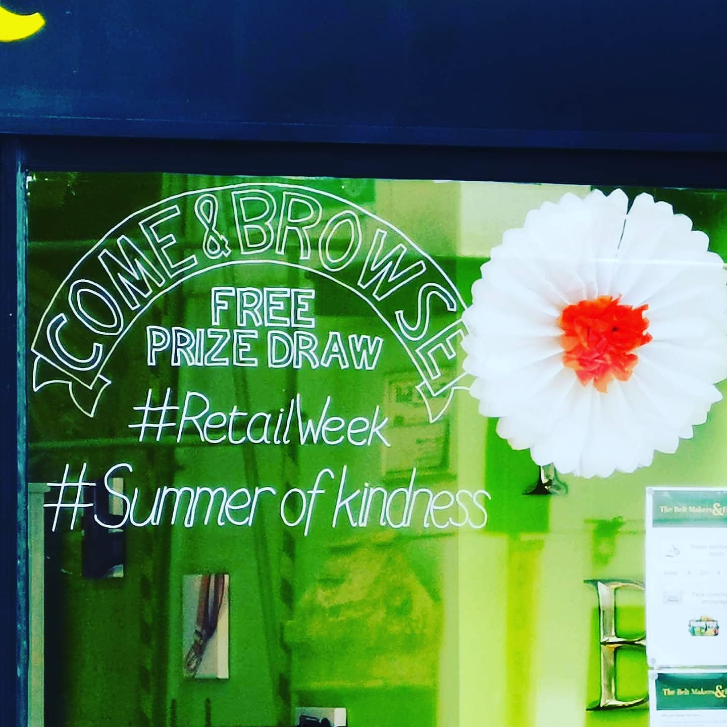 Close up of our shop window with handwritten chalk pen banner stating Come & Browse, Free Prize Draw, #RetailWeek, #SummerofKindness